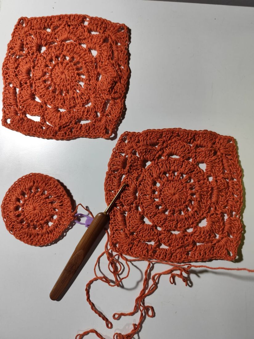 Squares de crochet em terracota com agulha de bambu sobre a mesa de trabalho